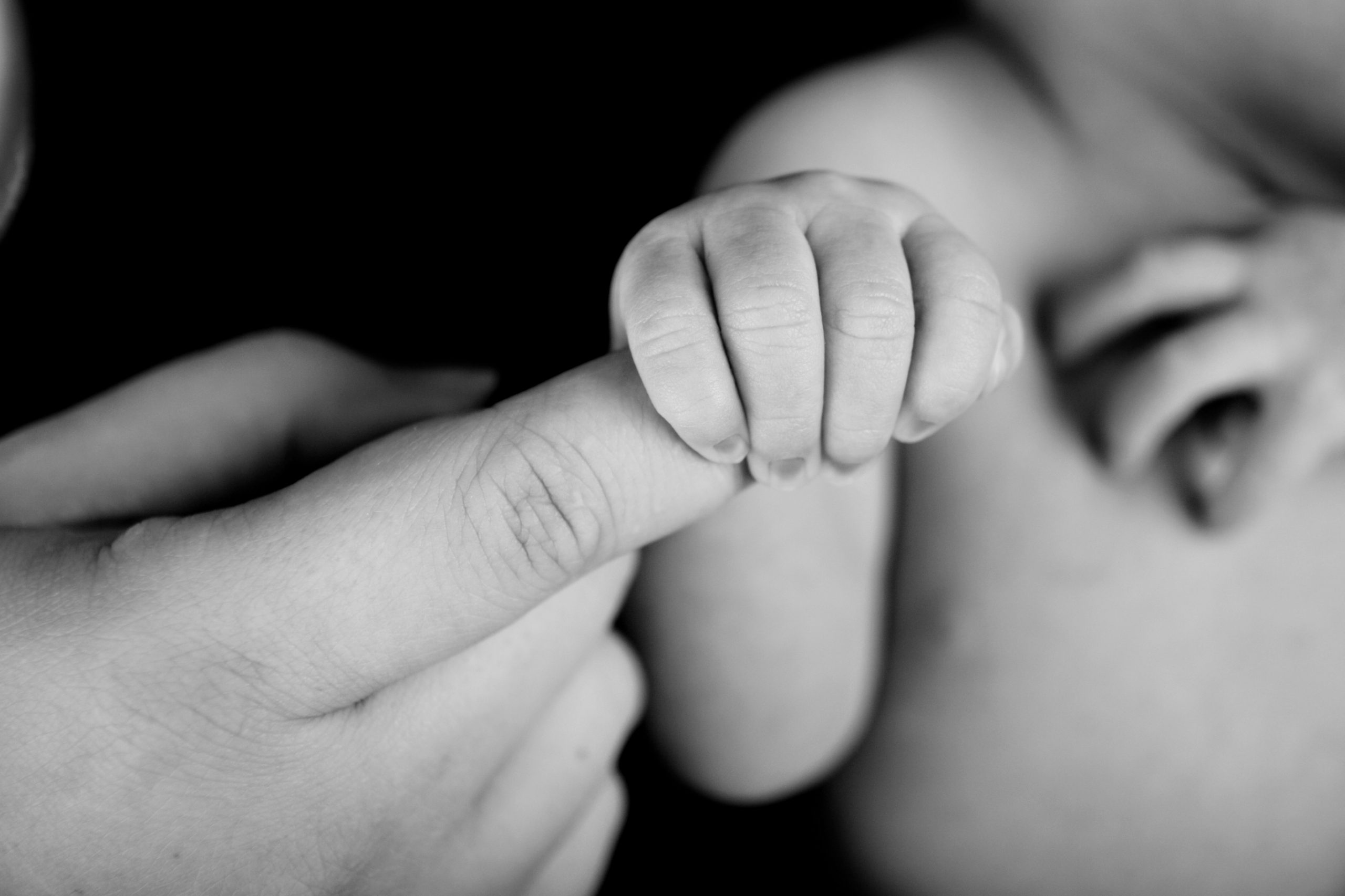 Twee babyvoetjes teder vastgehouden in de handen van een volwassene